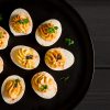 Gekookte Eieren Gevuld Met Dooier Met Mayonaise, Op Een Zwart Bord.