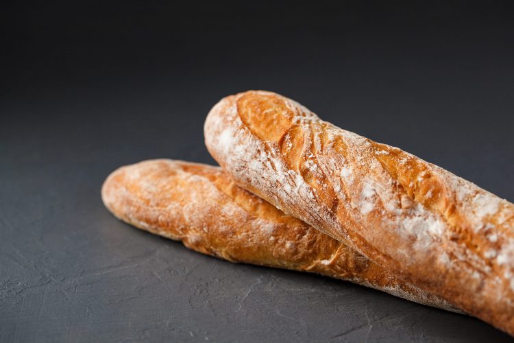 Bijgesneden foto van twee Franse baguettes op grijze textuurachtergrond, selectieve focus