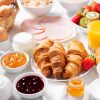 Ontbijt met croissants, koffie, sap, vlees, jam, granen en vers fruit op een houten tafel