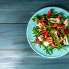 Salade met rucola, aardbeien en kaas brie, camembert. Lange banner formaat. ruimte voor tekst. Vanaf bovenaanzicht gefotografeerd.