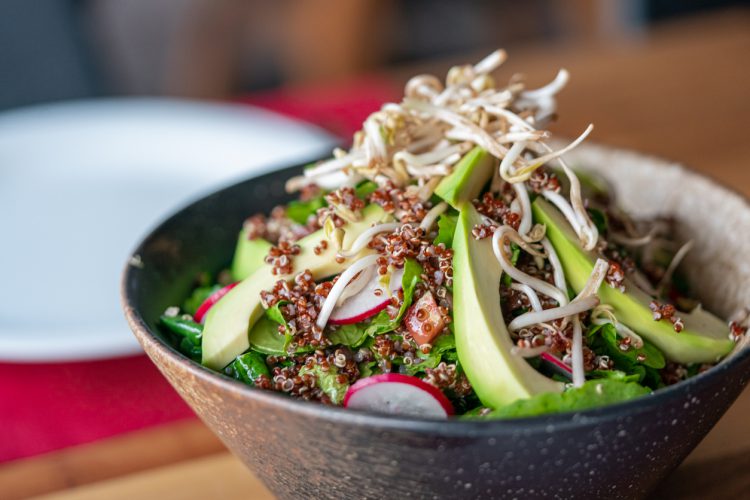 Traditionele avocadosalade met quinoa Gefotografeerd op een houtentafel.