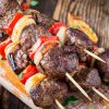 Spiesjes van gegrild shishkabab met groenten op houtenplankje. Vanuit zijaanzicht gefotografeerd.