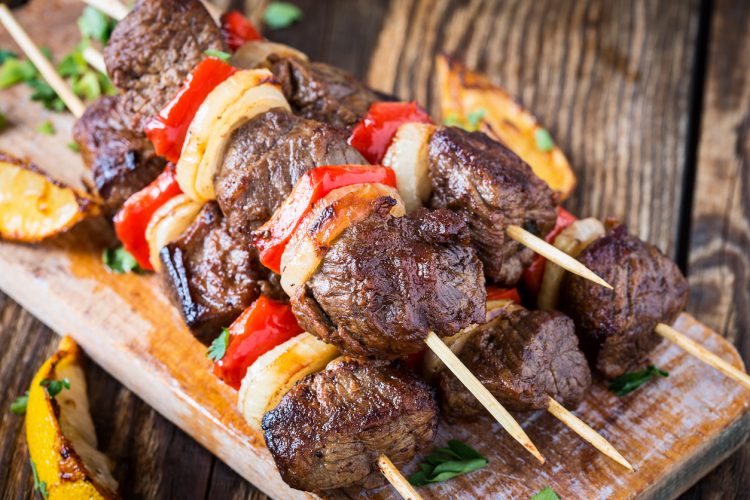 Spiesjes van gegrild shishkabab met groenten op houtenplankje. Vanuit zijaanzicht gefotografeerd.